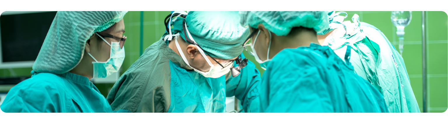 Three surgeons, in their scrubs, performing surgery